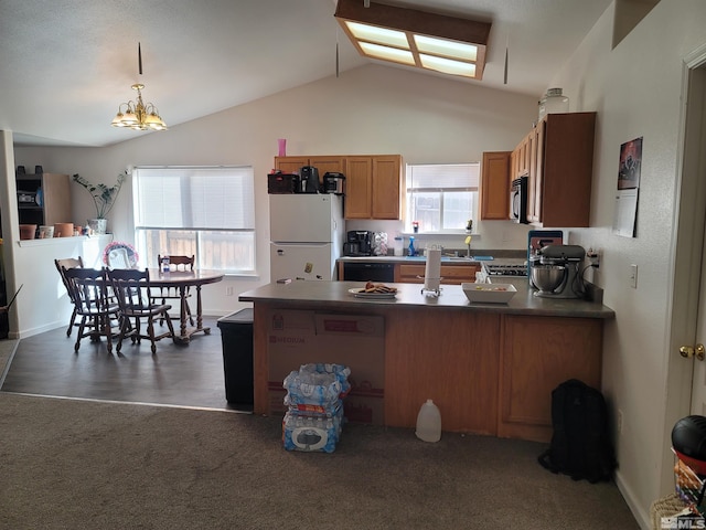 kitchen featuring a peninsula, vaulted ceiling, brown cabinetry, freestanding refrigerator, and stainless steel microwave