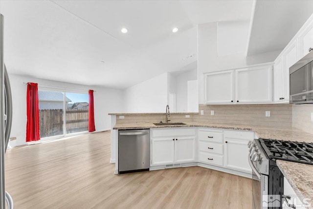 kitchen featuring tasteful backsplash, appliances with stainless steel finishes, light wood-style floors, white cabinets, and a sink