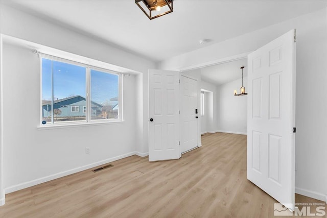 empty room with light wood-style flooring, visible vents, and baseboards