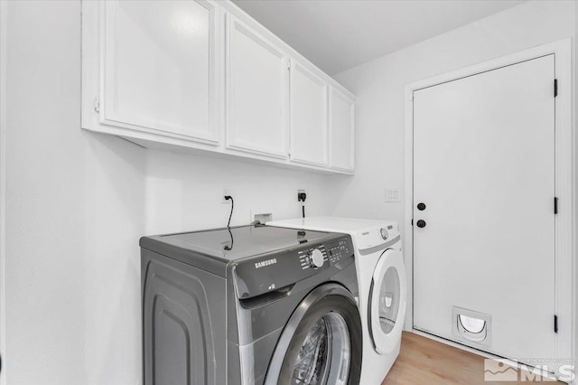 clothes washing area featuring light wood-type flooring, washing machine and dryer, and cabinet space