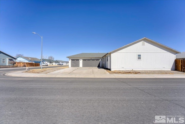 view of front of house featuring driveway, a garage, a residential view, and fence