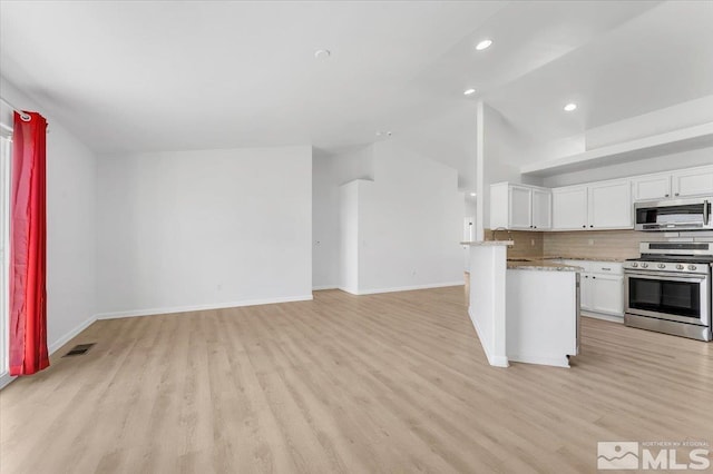 kitchen with tasteful backsplash, vaulted ceiling, stainless steel appliances, light wood-style floors, and white cabinetry