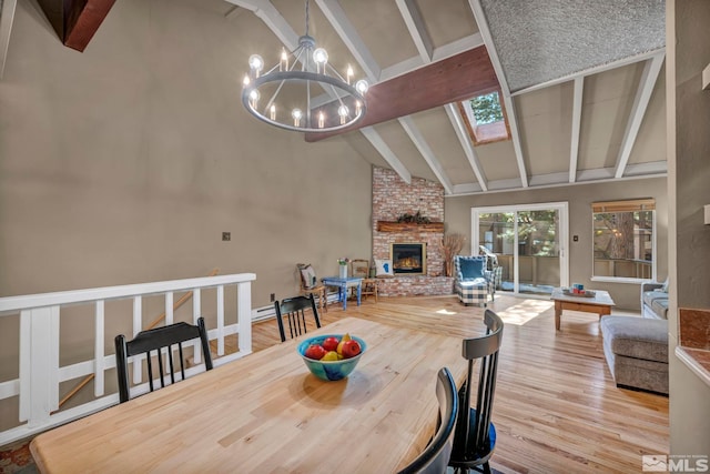 dining space featuring a fireplace, high vaulted ceiling, a notable chandelier, and wood finished floors