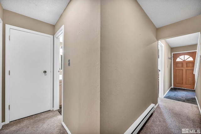 carpeted foyer featuring a baseboard heating unit, a textured ceiling, and baseboards