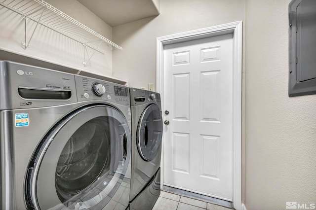 washroom with light tile patterned floors, laundry area, washer and clothes dryer, and electric panel