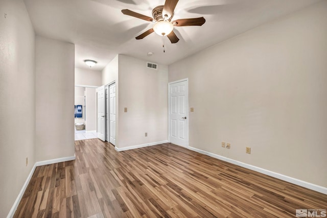 unfurnished room featuring a ceiling fan, baseboards, visible vents, and wood finished floors