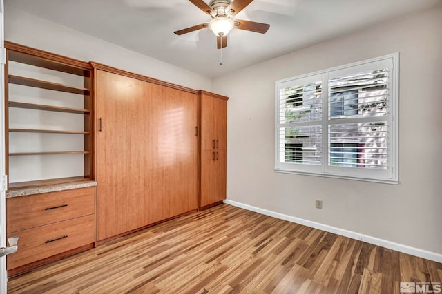 unfurnished bedroom featuring a ceiling fan, a closet, light wood-style flooring, and baseboards