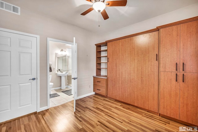 unfurnished bedroom featuring ensuite bathroom, light wood-type flooring, visible vents, and baseboards