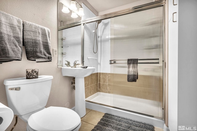 bathroom featuring a stall shower, toilet, and tile patterned floors