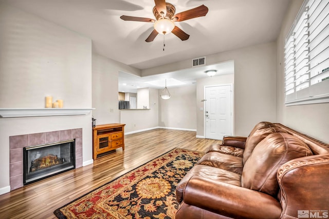 living room with visible vents, a fireplace, baseboards, and wood finished floors