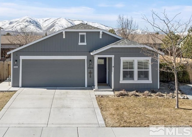 view of front of home with a mountain view, driveway, an attached garage, and fence