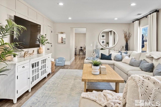 living area with recessed lighting, visible vents, and wood finished floors