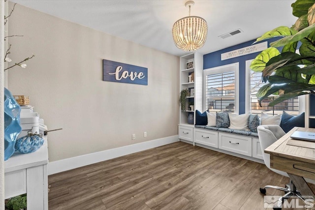 home office with an inviting chandelier, baseboards, visible vents, and wood finished floors