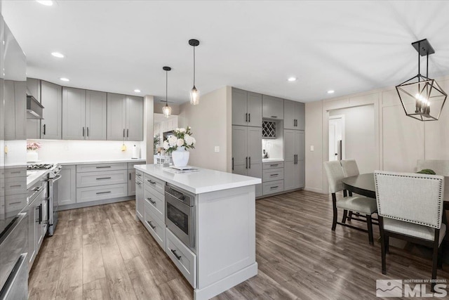 kitchen with stainless steel appliances, light countertops, gray cabinetry, and wood finished floors