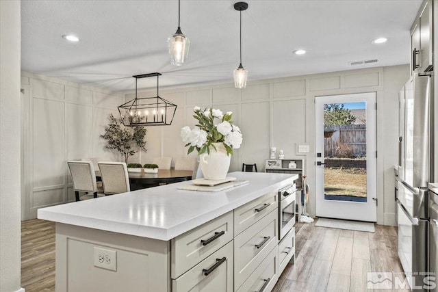 kitchen featuring light wood-style floors, stainless steel appliances, light countertops, and a center island