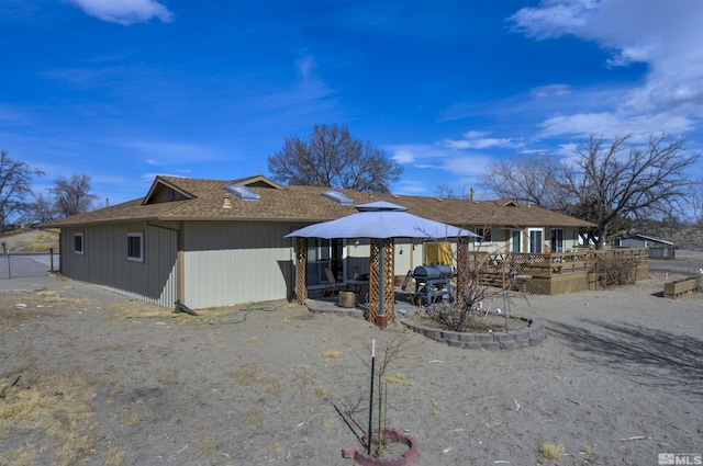 rear view of house with a deck and roof with shingles