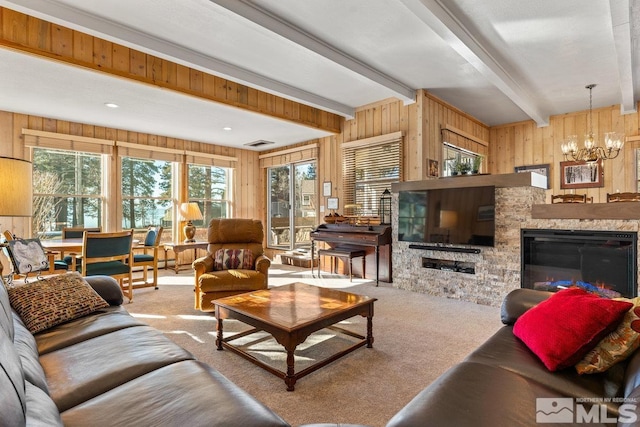 carpeted living room featuring a glass covered fireplace, beam ceiling, visible vents, and wooden walls