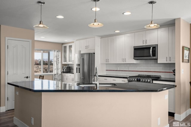 kitchen featuring appliances with stainless steel finishes, dark countertops, a sink, and backsplash