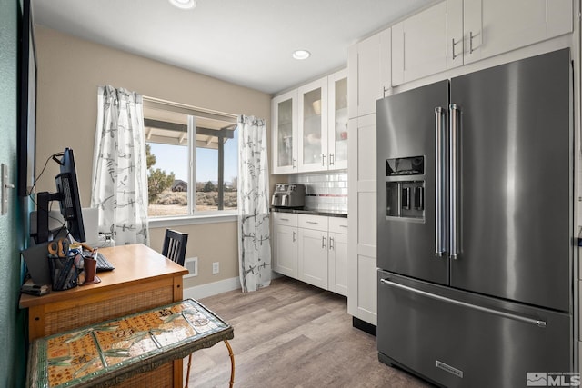 kitchen with decorative backsplash, glass insert cabinets, white cabinetry, high quality fridge, and light wood-type flooring