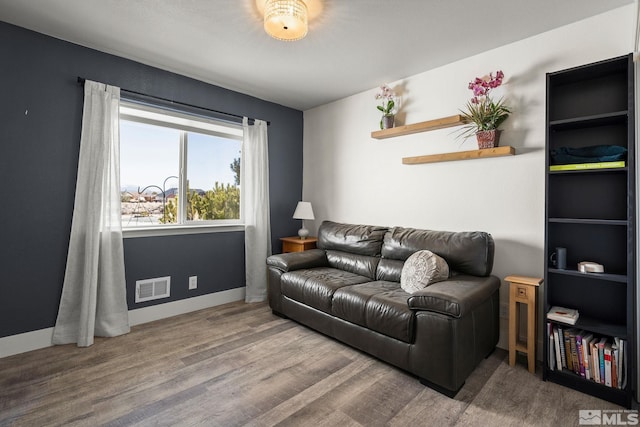 living room with baseboards, visible vents, and wood finished floors