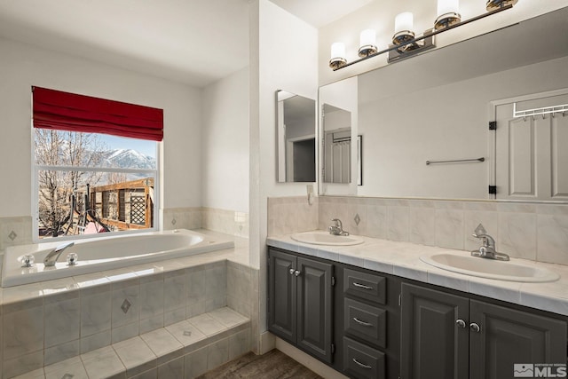 bathroom featuring double vanity, a garden tub, and a sink