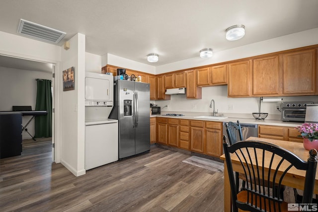 kitchen with stainless steel appliances, stacked washer / dryer, a sink, visible vents, and light countertops