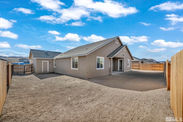 back of house with a fenced backyard, a patio, and stucco siding