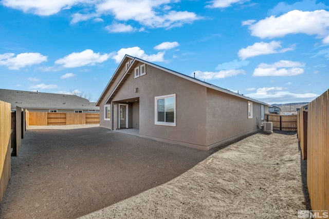 back of house with a patio area, central AC, a fenced backyard, and stucco siding