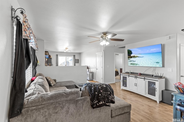 living area with a ceiling fan, light wood-type flooring, and baseboards