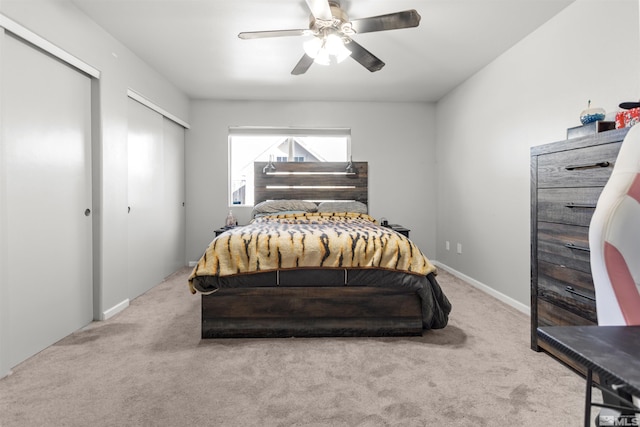 carpeted bedroom featuring ceiling fan, two closets, and baseboards