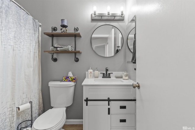 full bath featuring baseboards, vanity, and toilet