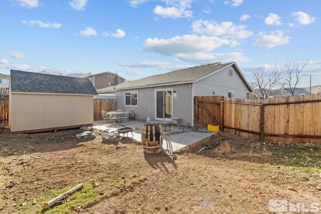 rear view of house featuring a patio area, an outdoor structure, a fenced backyard, and a shed