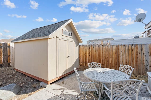 view of shed with fence and outdoor dining area