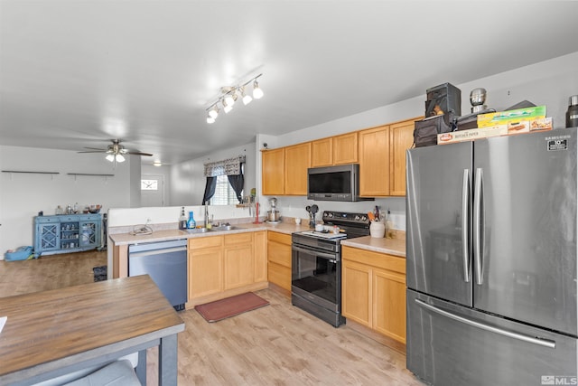 kitchen with stainless steel appliances, a sink, light wood-style floors, light countertops, and light brown cabinetry