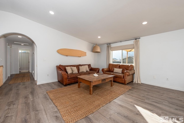 living area with arched walkways, baseboards, wood finished floors, and recessed lighting