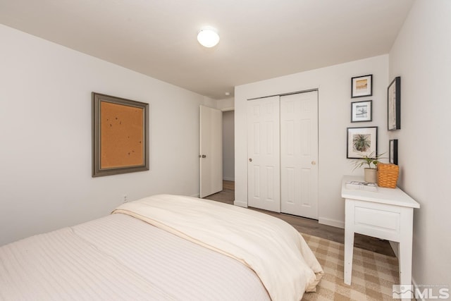 bedroom with light wood finished floors, a closet, and baseboards