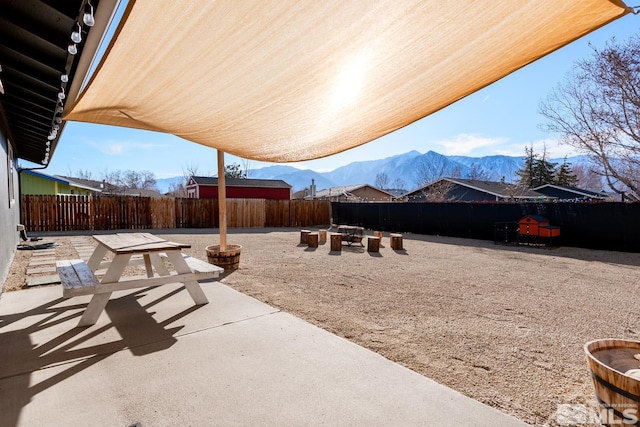 view of patio / terrace with a fenced backyard, a mountain view, and a fire pit