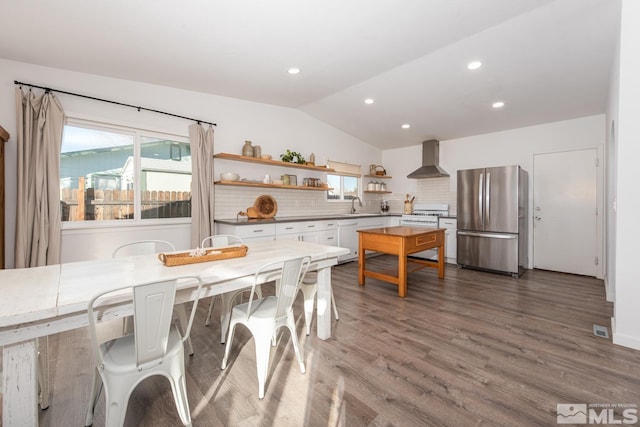 kitchen featuring lofted ceiling, open shelves, a healthy amount of sunlight, freestanding refrigerator, and wall chimney exhaust hood