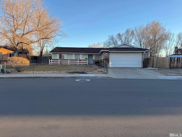 single story home featuring a garage, concrete driveway, and a fenced front yard