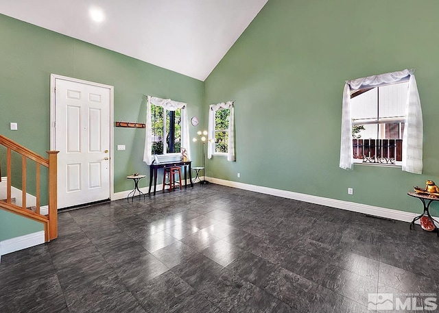 empty room featuring high vaulted ceiling, baseboards, and stairway