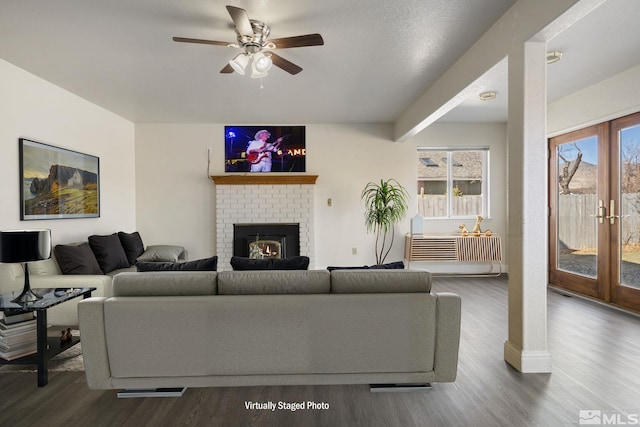 living room with a fireplace, a ceiling fan, wood finished floors, and french doors