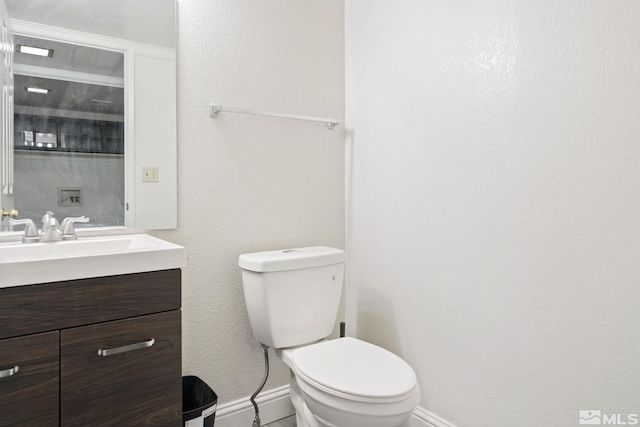 bathroom featuring toilet, baseboards, and vanity