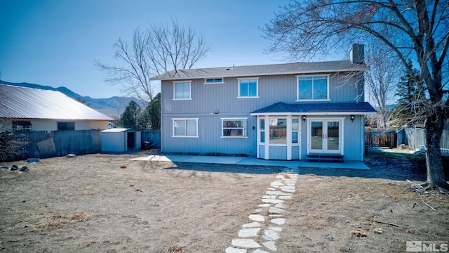 back of property featuring a storage shed, a fenced backyard, a chimney, and an outbuilding