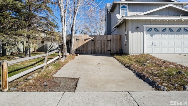 view of property exterior with concrete driveway, fence, an attached garage, and a gate