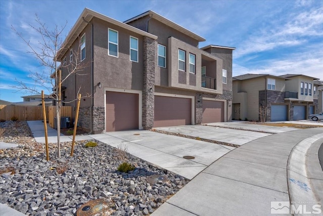 view of front of property with concrete driveway, stone siding, a residential view, an attached garage, and stucco siding