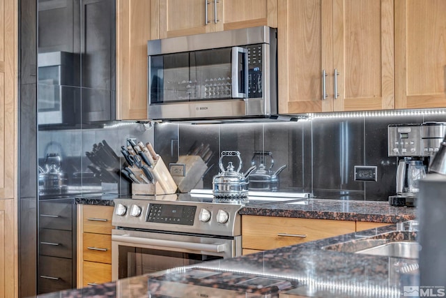 kitchen with appliances with stainless steel finishes, dark stone countertops, and backsplash