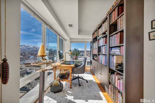 office area with bookshelves, visible vents, and wood finished floors