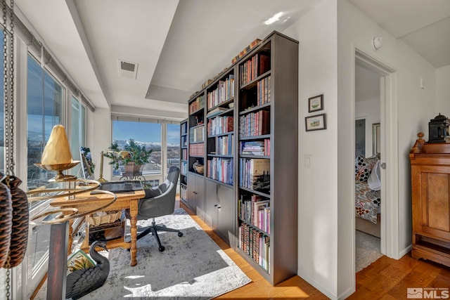 office area featuring baseboards, visible vents, and wood finished floors