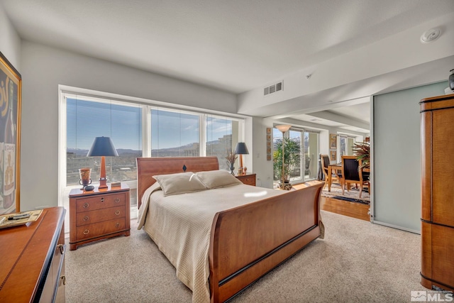 bedroom with visible vents and light carpet