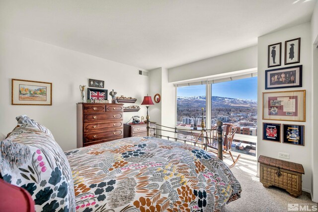 carpeted bedroom with visible vents, a mountain view, and access to exterior